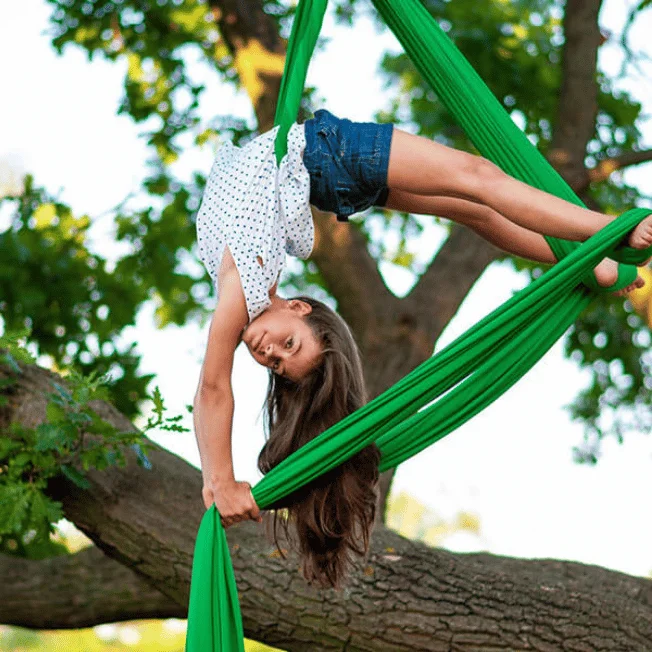 Child practising aerial silk outdoors.
