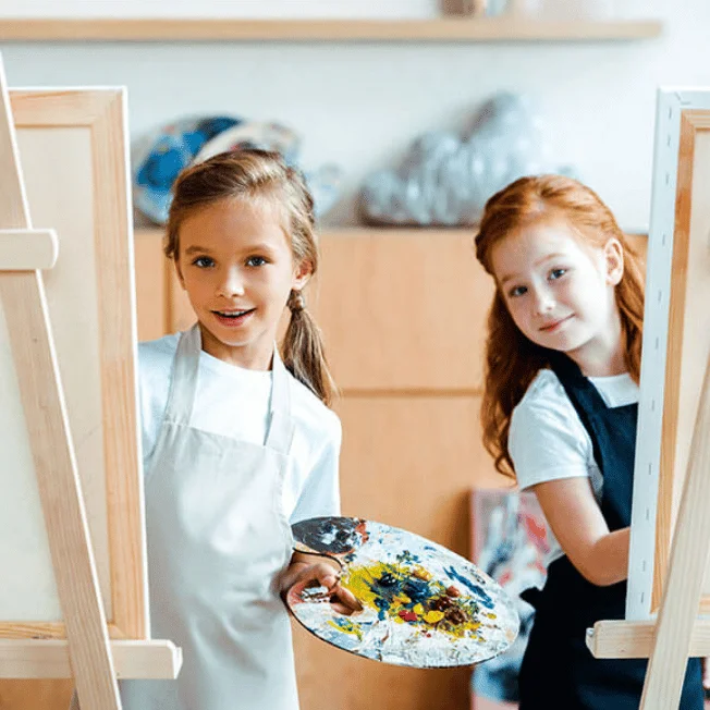 Children painting at easels during an art workshop.
