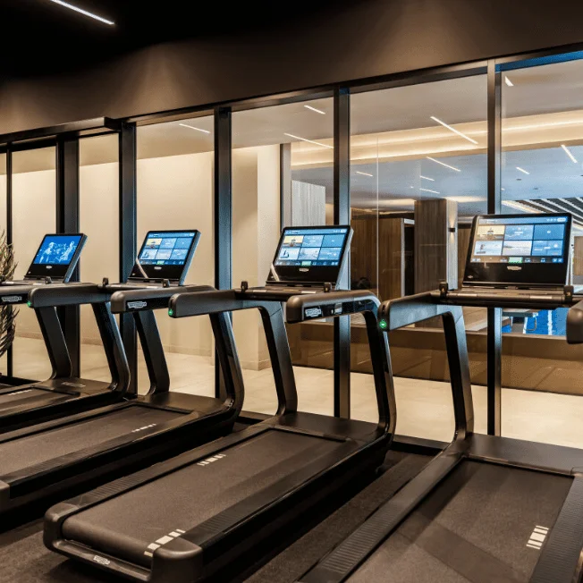 Ein modernes Fitnesszentrum mit Laufbändern und Blick auf den Innenpool im Pical Resort 5*.