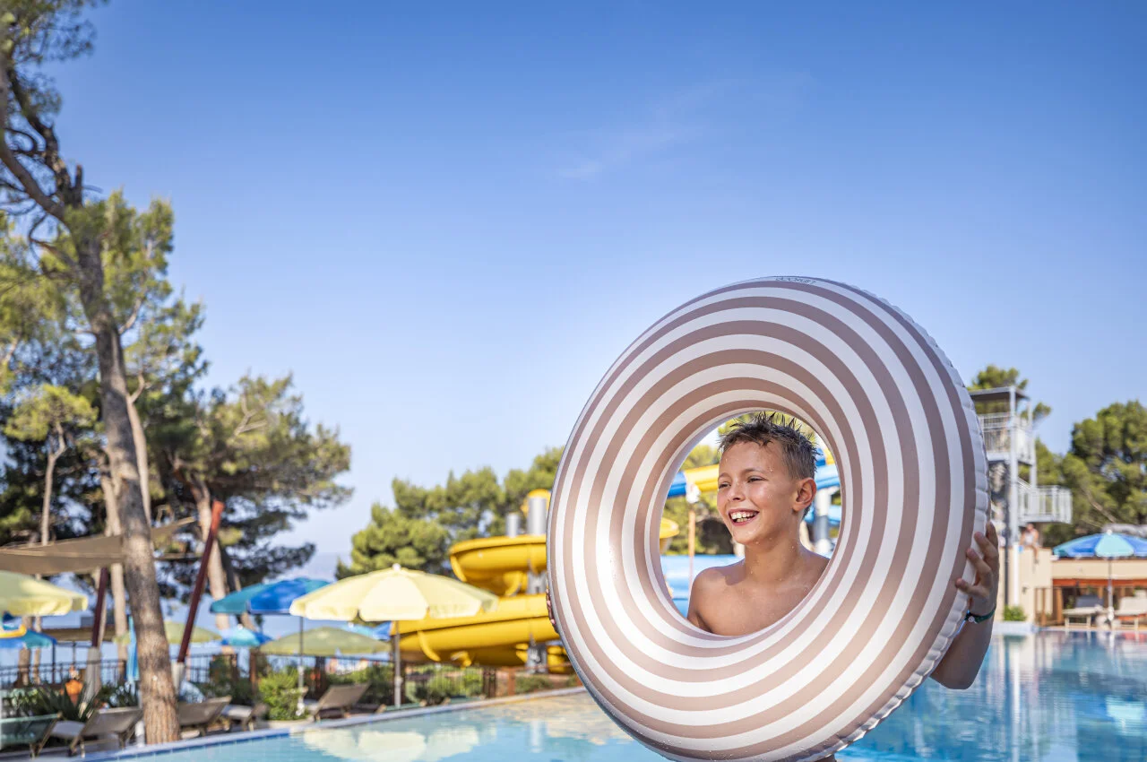 Child enjoying the pool at Sunny Makarska by Valamar while playing with a large inflatable ring.
