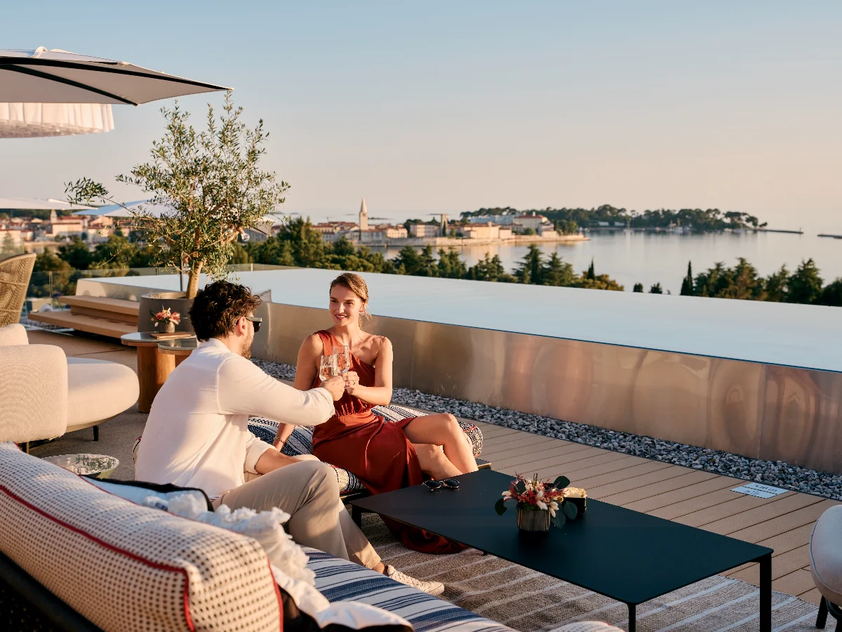 Par uživa u piću u Pical Rooftop Baru by Laurent-Perrier uz pogled na Poreč i Jadran pred zalazak sunca.