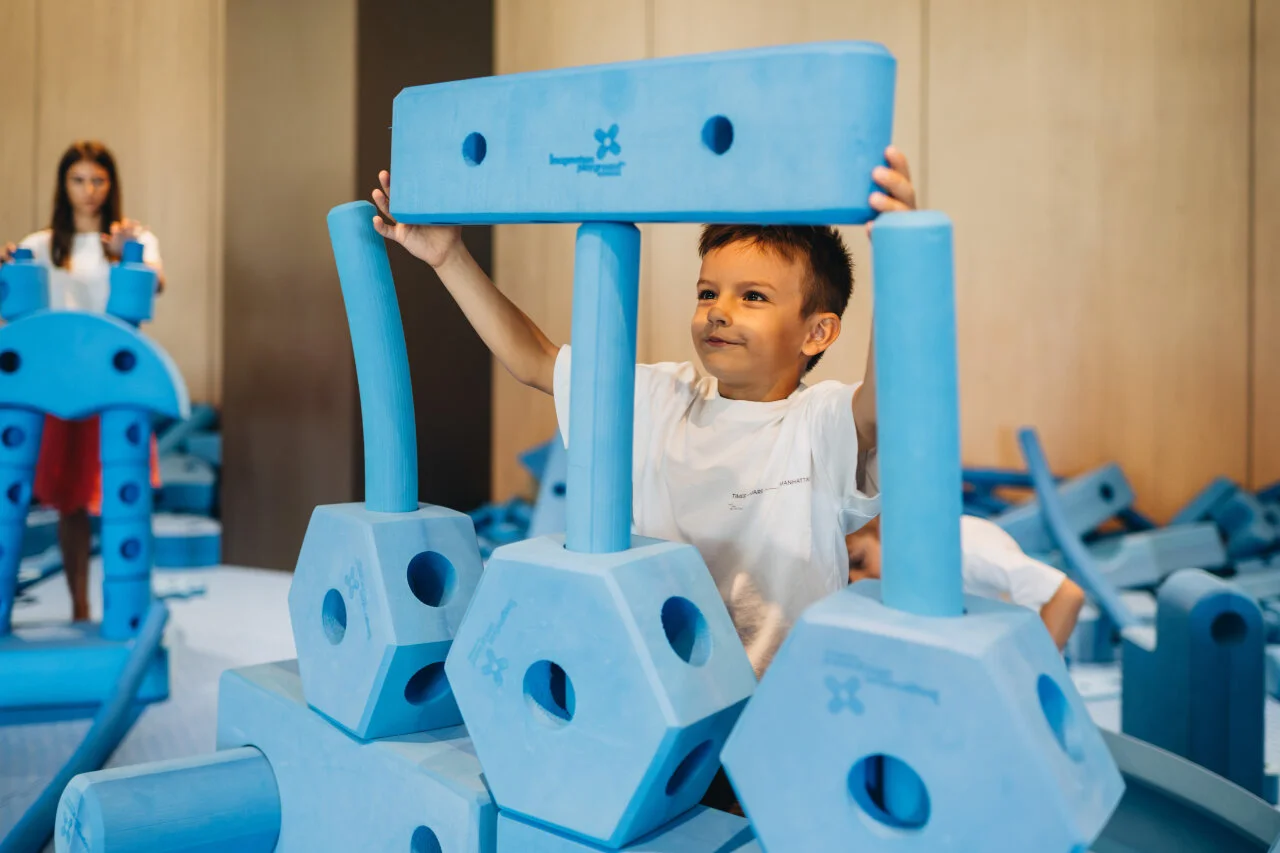 Boy building a structure with large blue soft blocks in the children’s playroom at Pical Resort.