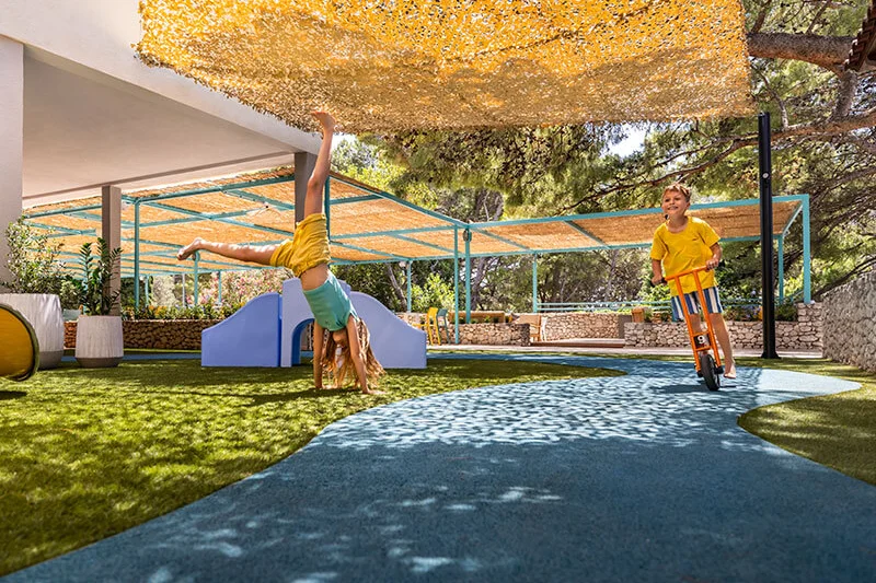 Children playing in the shaded outdoor play area.
