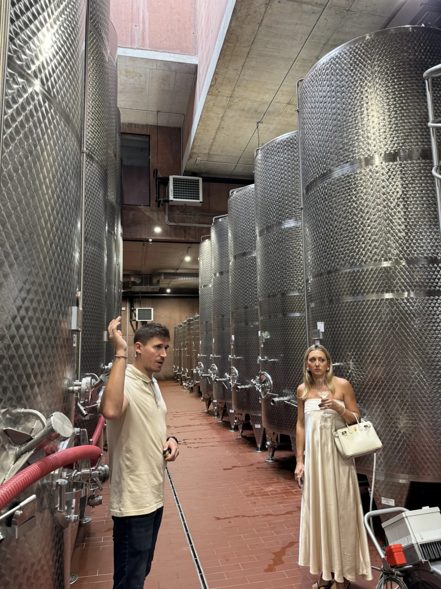 Visitors exploring the wine production area at Deklić Winery, surrounded by large stainless steel fermentation tanks.