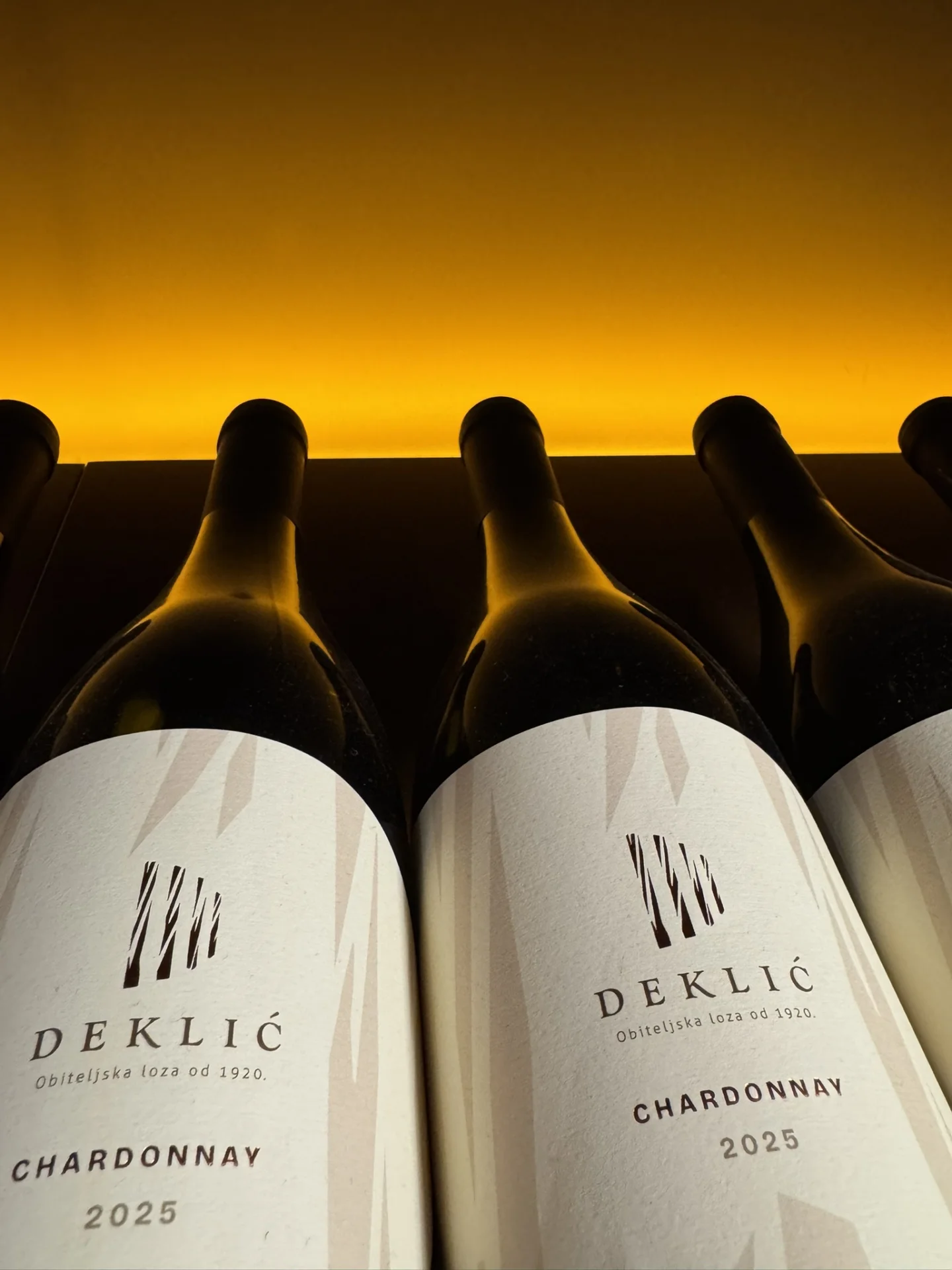 Bottles of Deklić Chardonnay 2025 displayed against a warm golden background at Deklić Winery in Istria.