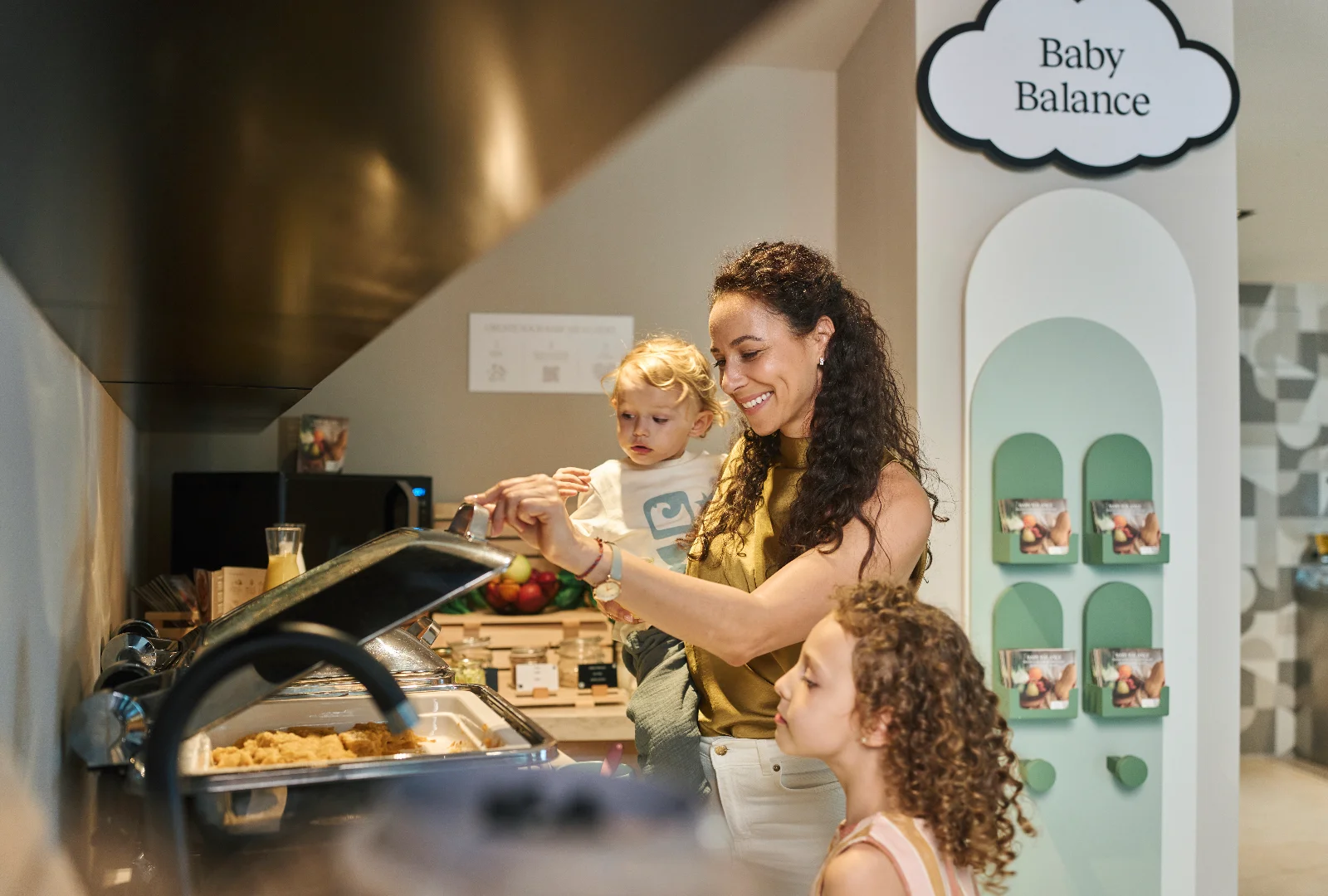 A parent choosing food for their children at a hotel buffet.