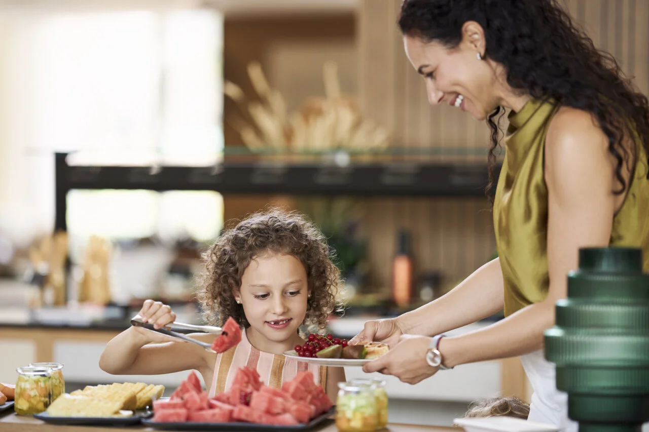 Mother and child preparing fresh fruit together in the kitchen.