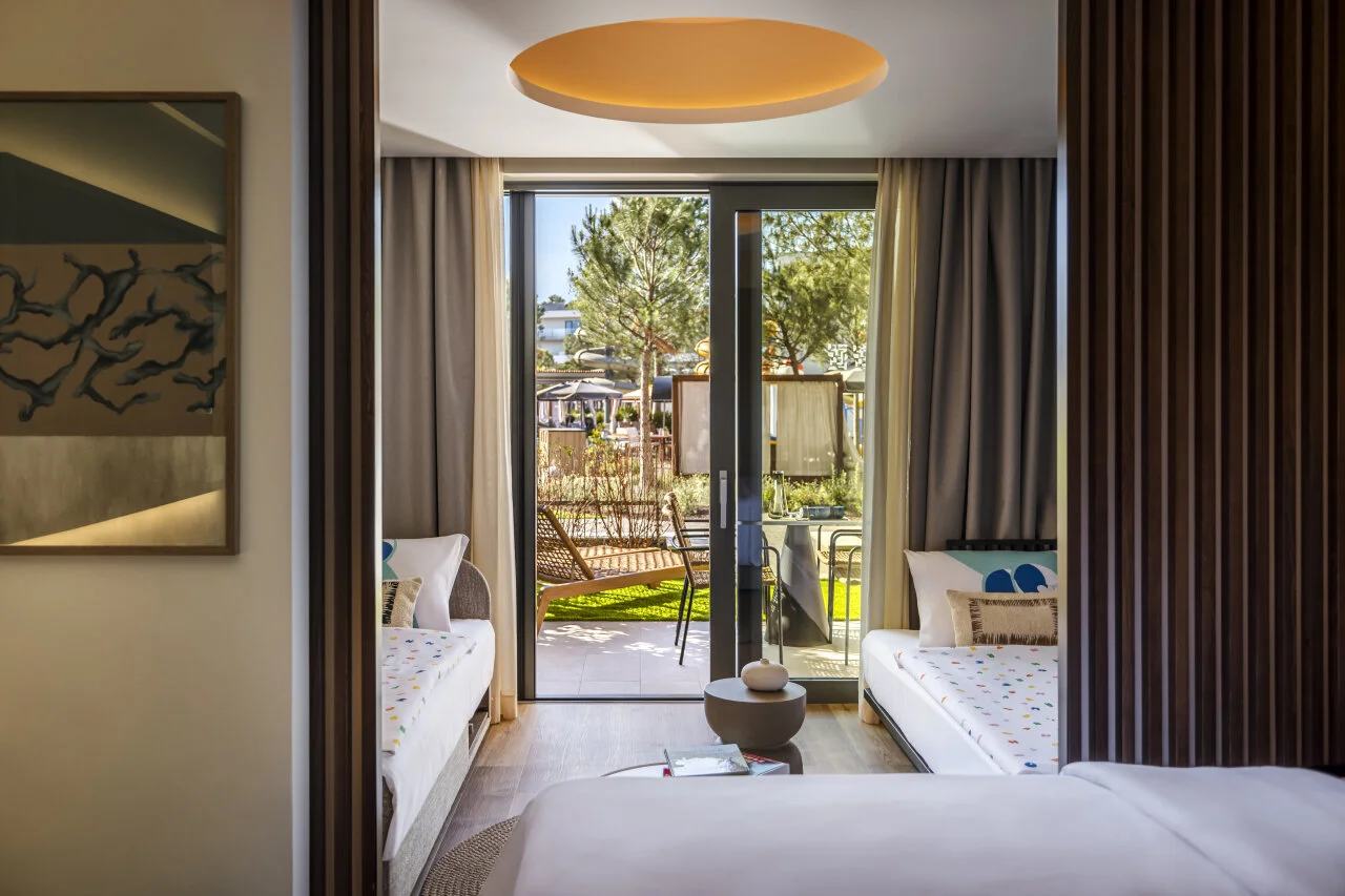 Modern hotel room with access to a balcony overlooking greenery.
